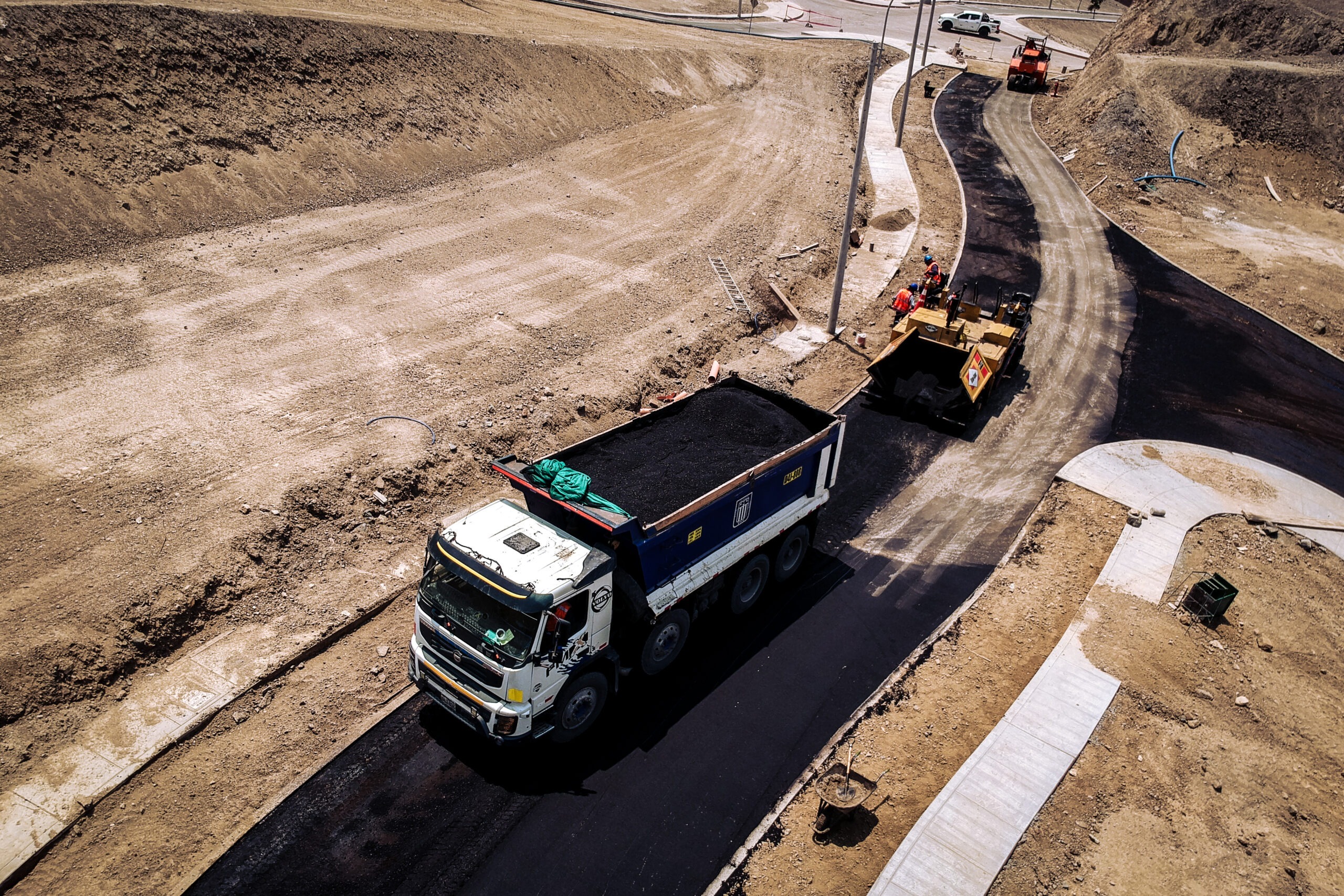 Vista aérea de volquete y pavimentadora en obra vial, Asfaltec Perú